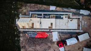Letecký pohled na rozestavěnou CLT konstrukci, základovou desku a montážní zázemí projektu Za lány.