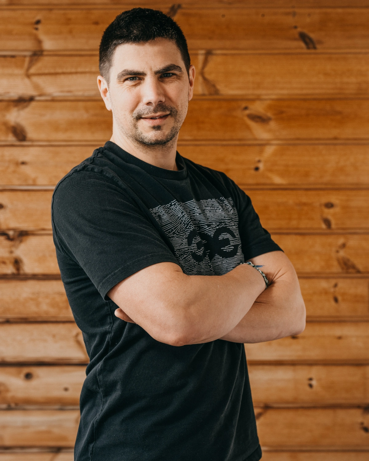 Portrét architekta projektu Za lány Lukáše Pejsara před dřevěnou stěnou.